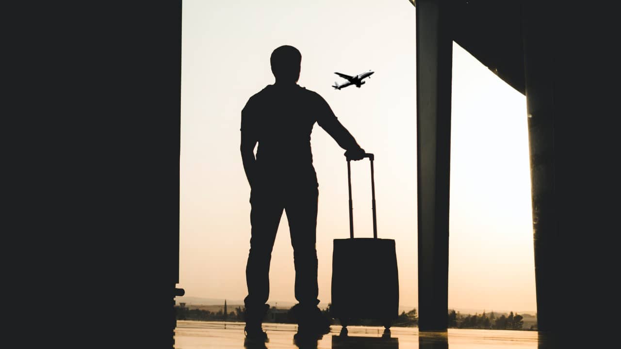 Man standing watching an airplane take off